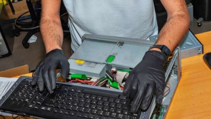 Man typing on a computer keyboard with plastic gloves